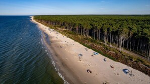 A beach with a forested area and a road parallel to the shore. - Holiday Home With Terrace, Large Garden (Choczewo)