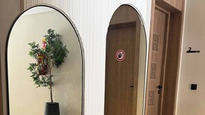 Een gang met een zwart-wit geruit vloerkleed, een potplant en een deur met een verboden toegangsbordje.