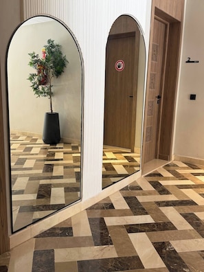 Un couloir avec un sol à carreaux, une plante en pot et une porte sur laquelle est apposée une pancarte indiquant « accès interdit ».