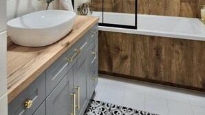Ein modernes Badezimmer mit einer Holzvertäfelung, einem weißen Waschbecken und einer Badewanne.