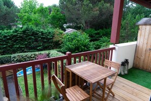 A wooden deck with a table and chairs, surrounded by greenery and a wooden fence. - Me Lady's Cocoon 3-Star (Capbreton)