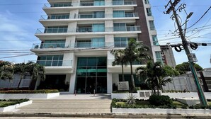 Un edificio de gran altura con varios balcones, una entrada amplia y un letrero que indica 'High Tower'.