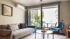 Un soggiorno moderno con un divano, un tavolino rotondo, una poltrona blu e vista all'esterno.