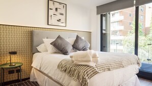 Un letto rifatto con cuscini, una lampada da comodino e una coperta.