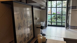 Una cocina con una ilustración botánica enmarcada, una máquina de café y una ventana que ofrece vistas de zonas verdes.
