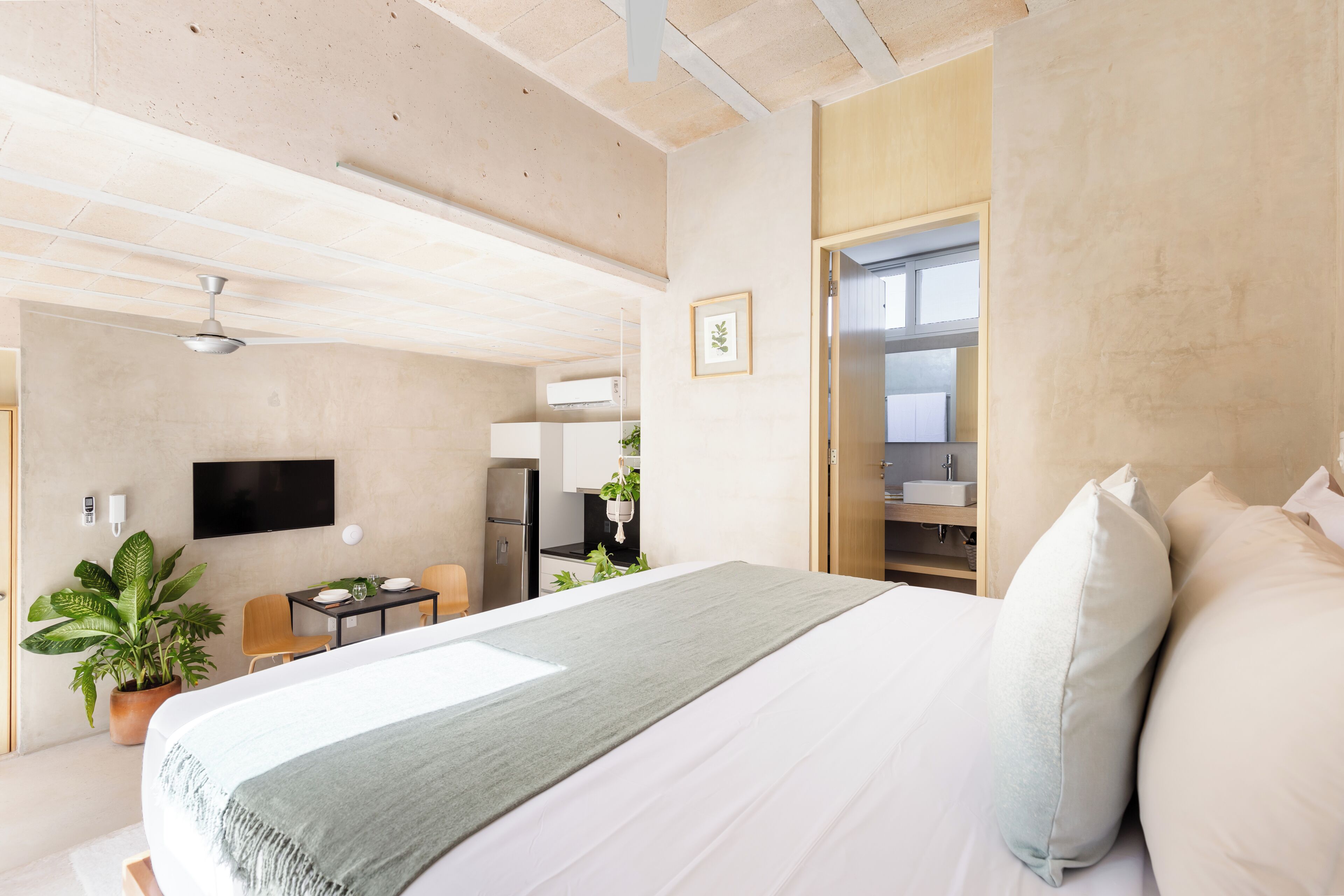 Een moderne hotelkamer met een groot bed, een bureau, een stoel, een televisie en een zichtbare badkamer door een geopende deur.