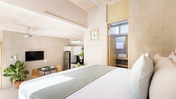 Een moderne hotelkamer met een groot bed, een bureau, een stoel, een televisie en een zichtbare badkamer door een geopende deur.