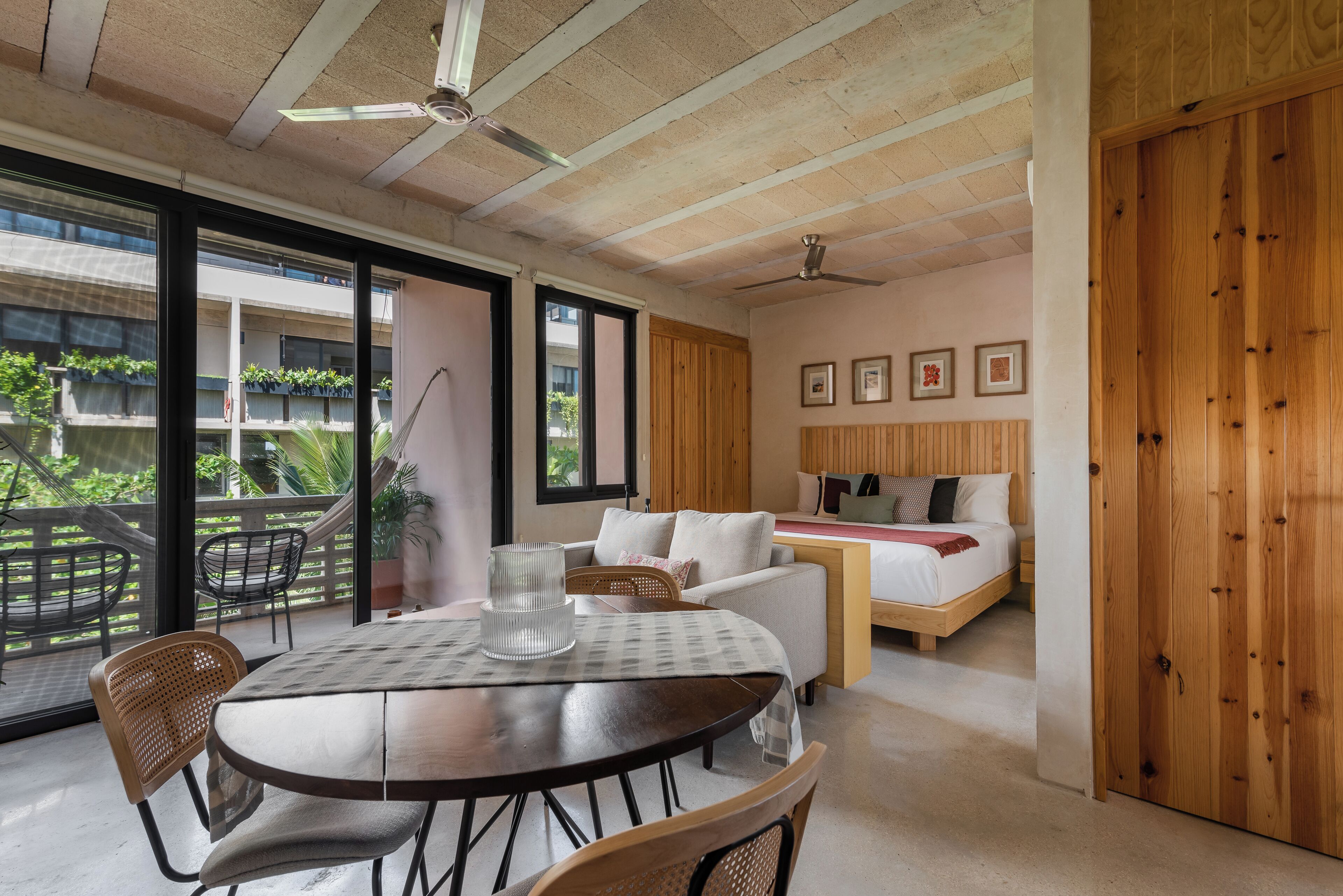 Une chambre moderne comprenant un coin repas, un lit et un balcon aménagé avec du mobilier d’extérieur.