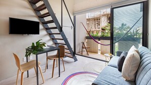 Un espacio habitable moderno con escalera, televisor de pantalla plana, comedor y sofá con cojines.
