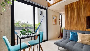 Una sala de estar moderna con un sofá, dos sillones, una mesa de comedor y un ventanal grande.