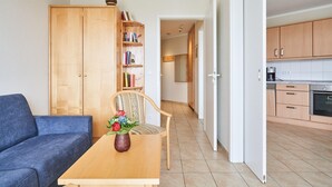 Ein modernes Wohnzimmer mit einer Couch, einem Holztisch mit einer Vase und einem Bücherregal.