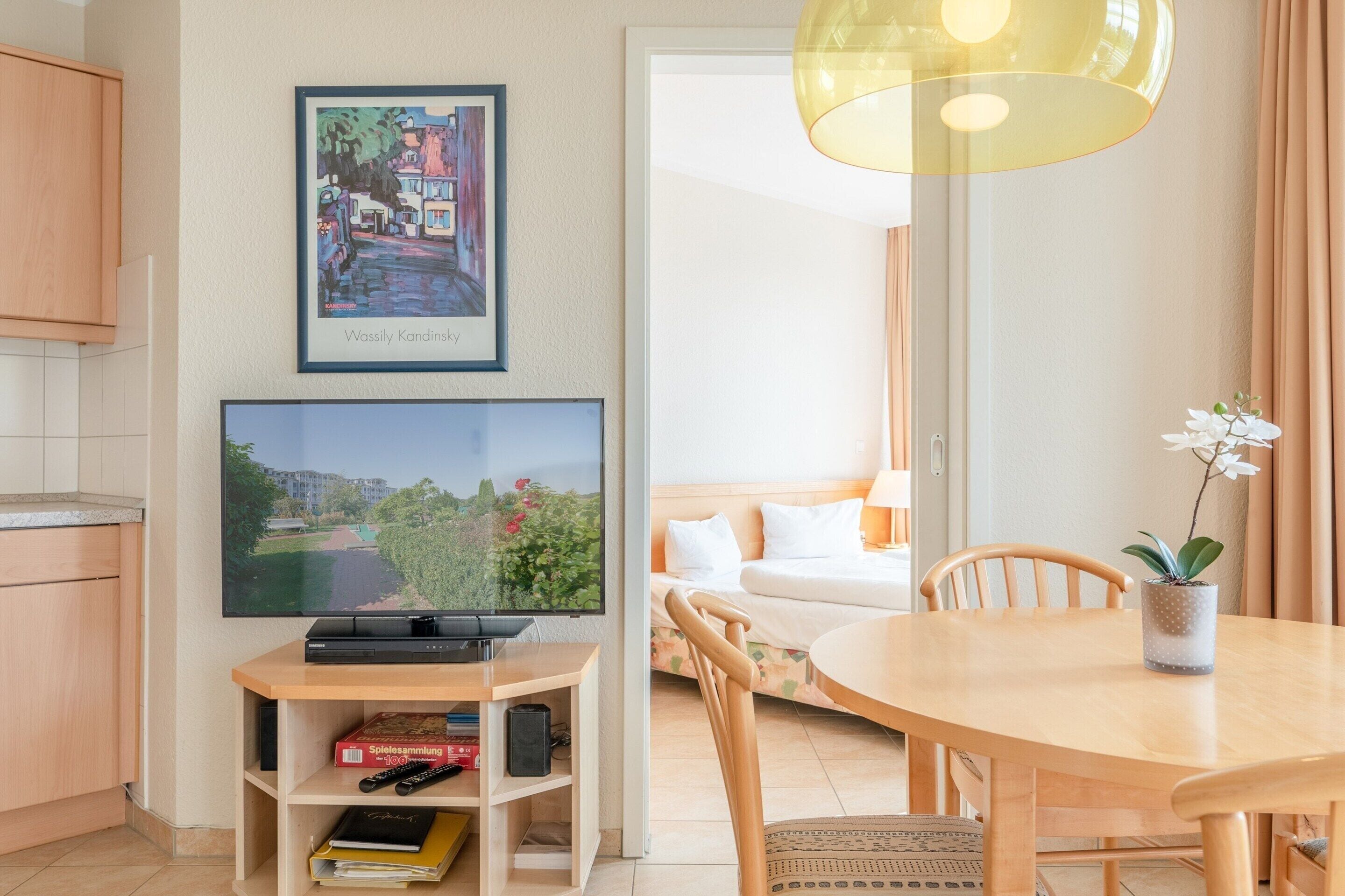 A modern living room with a flat-screen TV, a dining table, and a sofa.