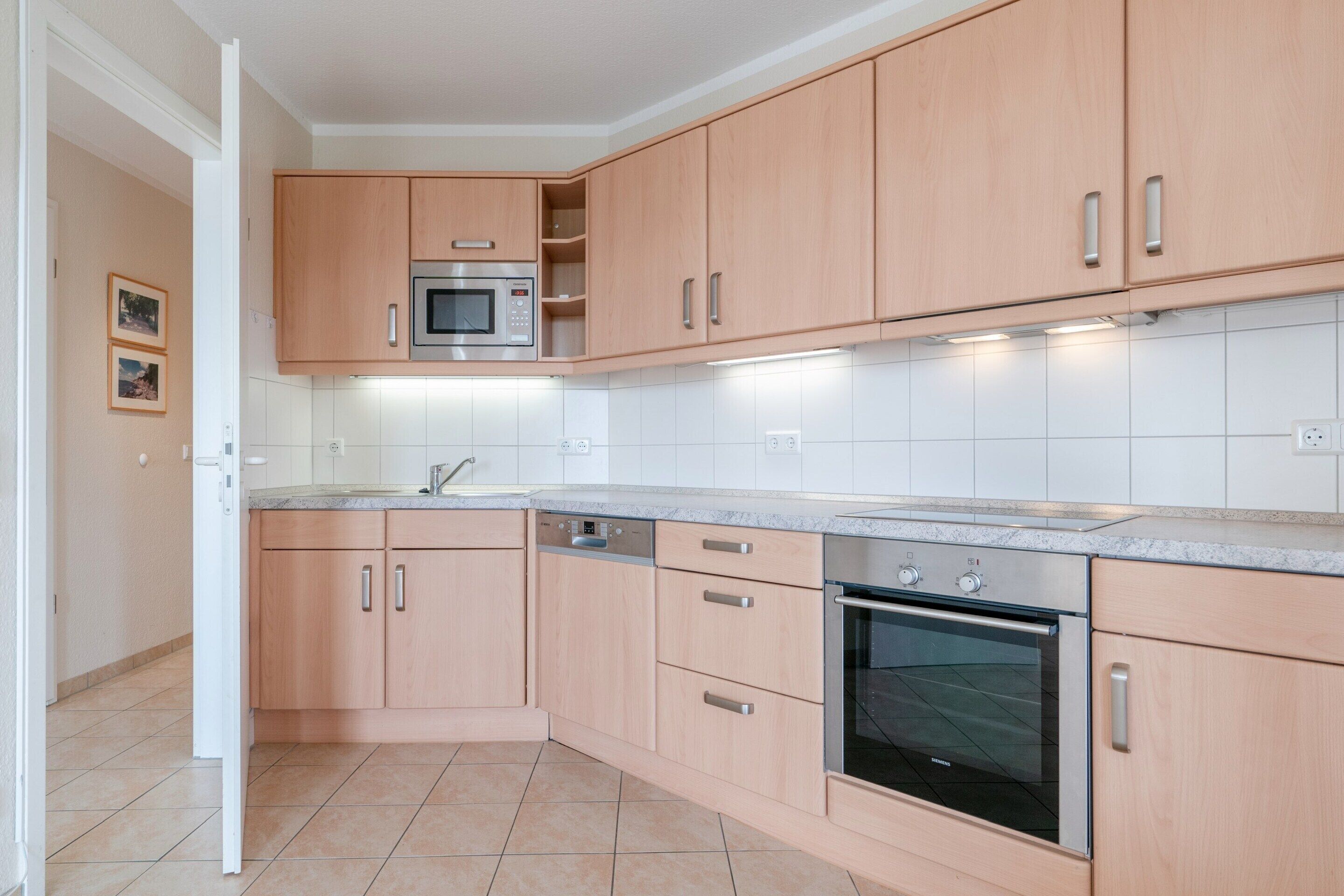 Una cocina moderna con armarios de madera, un microondas integrado, un lavavajillas y un horno.
