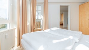 Ein Hotelzimmer mit Bett, Stuhl, Holztür und Fenster.