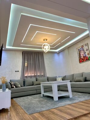 Un soggiorno moderno con un divano componibile, un tavolino da caffè e un soffitto con illuminazione geometrica.