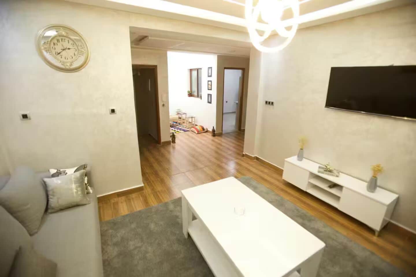 Un soggiorno con un divano, un tavolino, una televisione e una sveglia appesa al muro.