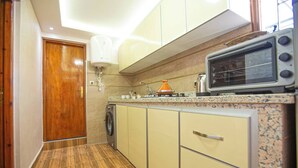 Een kleine keuken met een magnetron, spoelbak en wasmachine.