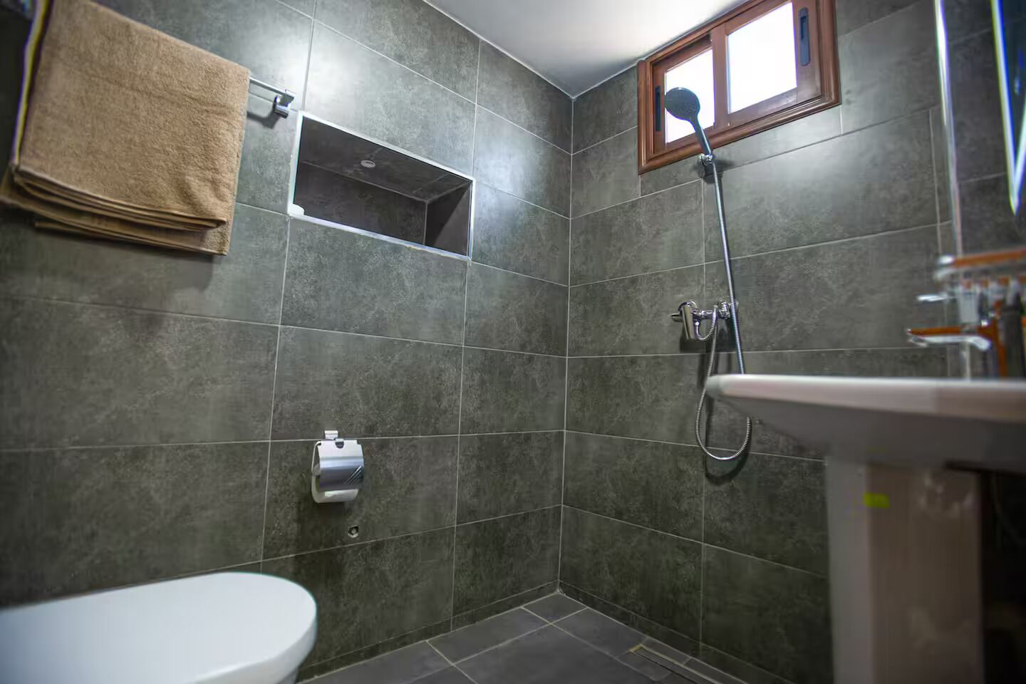 Ein Badezimmer mit Toilette, Waschbecken, Dusche und Handtuchhalter.