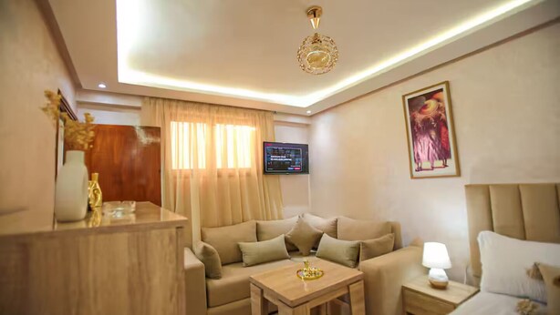 Hotelkamer met een bank, een tafeltje, een bedlamp, een televisie en een decoratief object op het dressoir.