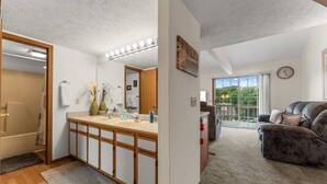 Ein Badezimmer mit einem Holzbadezimmerhocker, einem großen Spiegel und einem Duschbereich.