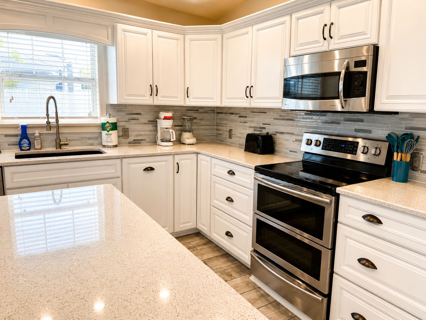 A modern kitchen with white cabinets, stainless steel appliances, and a granite countertop.
