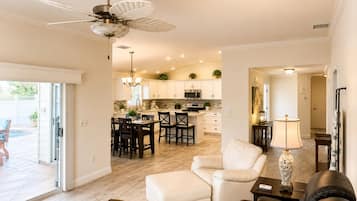 A modern living room with a sofa, a coffee table, and a dining area with chairs and a table.