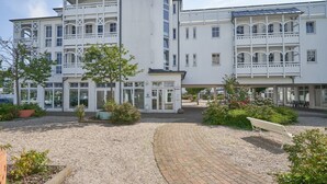 A multi-story building with a central entrance, surrounded by a gravel courtyard and potted plants. - Ferienwohnung im 2.og mit Balkon in Sellin (Sellin)