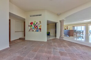 A spacious interior with a tiled floor, a colorful abstract mural, and a view of the ocean through large windows. - Villa del Palmar - Penthouse - 4BR/4BA - 6,600+ Sq.Ft! (Cabo San Lucas)