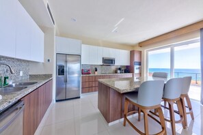 Eine moderne Küche mit Granit Arbeitsplatten, Edelstahlgeräten und einer großen Kochinsel mit Barhocker.