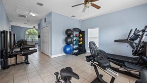 A home gym with exercise equipment, a ceiling fan, and a view of the outdoors. - Charming 3-bedroom townhome 20 mins from Disney! (Kissimmee)
