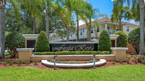 A landscaped area with a sign reading 'Fiesta Key,' surrounded by well-maintained hedges and palm trees. - Charming 3-bedroom townhome 20 mins from Disney! (Kissimmee)