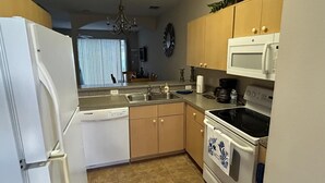 A kitchen with a refrigerator, dishwasher, microwave, stove, and cabinets. - Charming 3-bedroom townhome 20 mins from Disney! (Kissimmee)