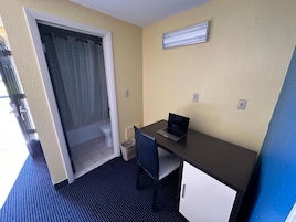 Una habitación pequeña con escritorio, silla y una puerta que da a un baño.