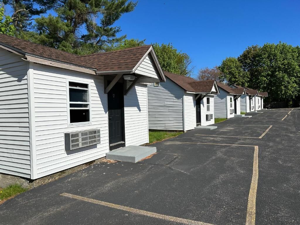 A row of single-story cabins with a parking lot in front.