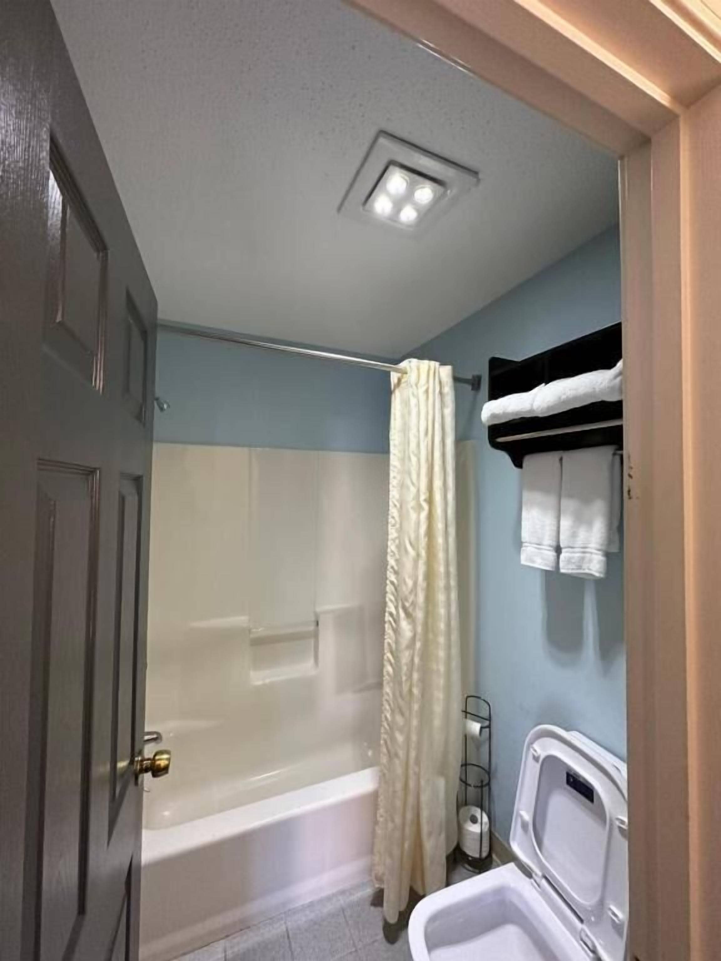 A bathroom with a bathtub, shower curtain, and a toilet.