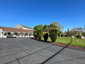A hotel with a parking lot, a building with a sloped roof, and a sign that reads 'Welcome Inn.'
