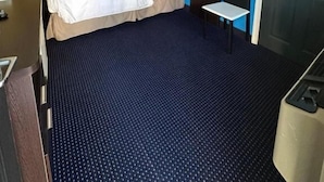 A hotel room with a bed, bedside table, and a desk with a chair.