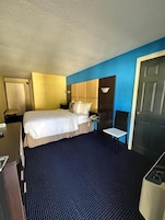 Una habitación de hotel con cama, mesita de noche y escritorio con silla.