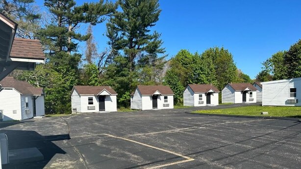 A row of small, single-story cabins with a parking lot in front. - WELCOME INN (North Kingstown)