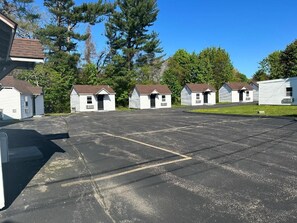 A row of small, single-story cabins with a parking lot in front. - WELCOME INN (North Kingstown)