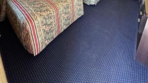A hotel room with two beds, a blue carpet, a ceiling with a light fixture, and a wardrobe. - WELCOME INN (North Kingstown)