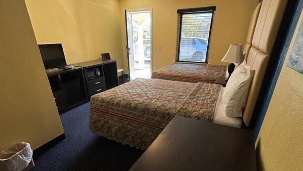 A hotel room with a bed, a desk, a chair, a TV, and a window.