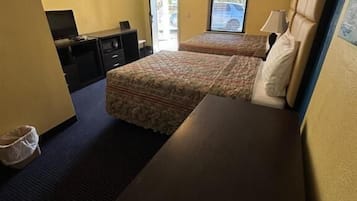 A hotel room with a bed, a desk, a chair, a TV, and a window.