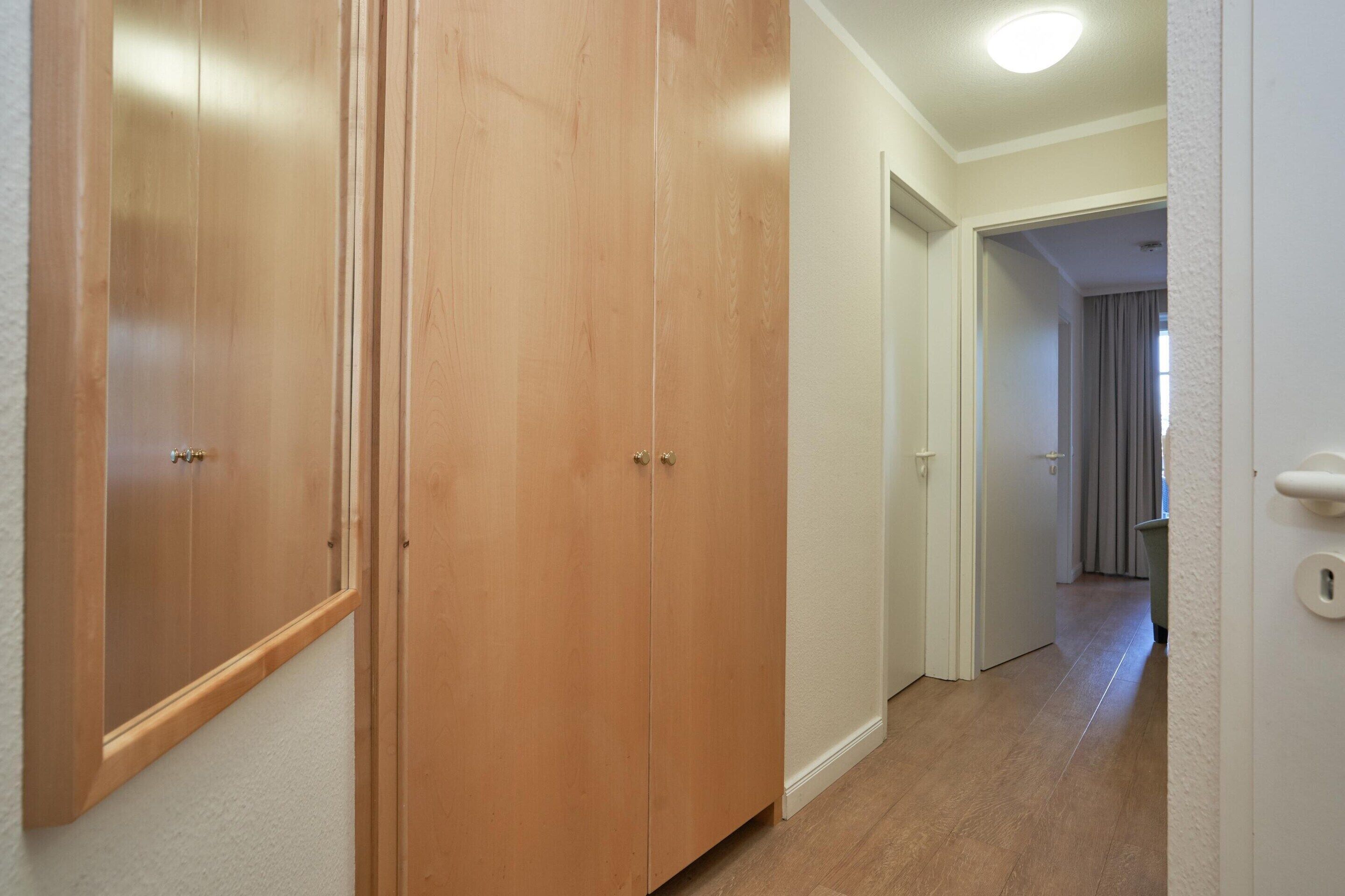 Ein Korridor mit Holztüren, einer weißen Wand und einer Tür mit Schlüsselloch.