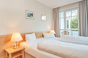 A hotel room with a bed, bedside lamps, a nightstand, and a window with curtains. - In Attraktiver Lage des Ostseebades Sellin (Sellin)