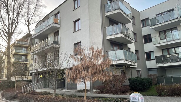 Um edifício residencial com vários andares, varandas, uma escadaria e um sinal de estacionamento.