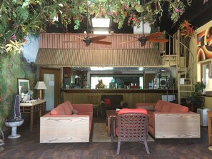 A bar area with wooden furniture, a seating area with cushioned sofas, and a decorative ceiling with hanging plants.