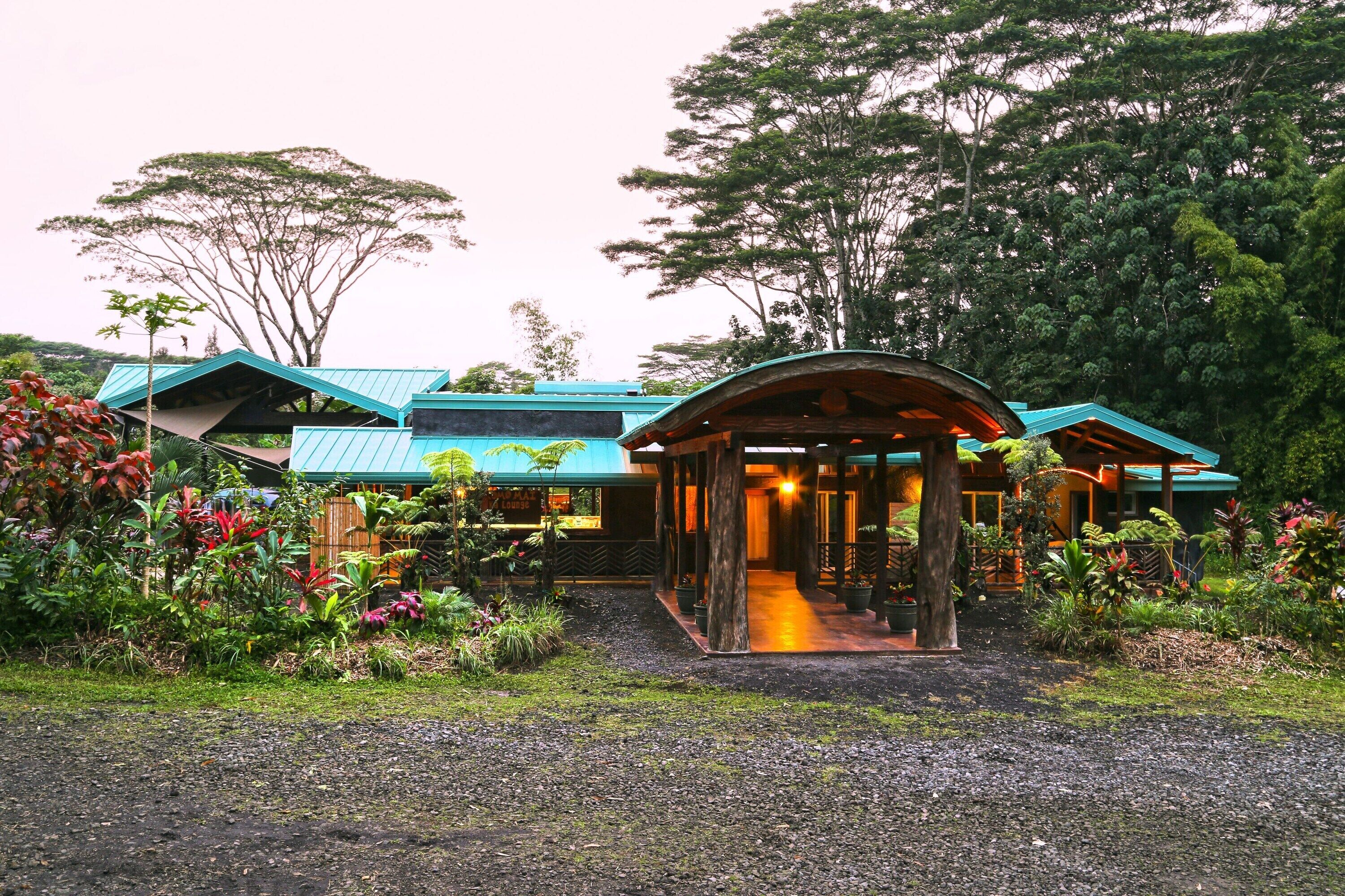 A building with a curved roof, surrounded by lush greenery and trees.