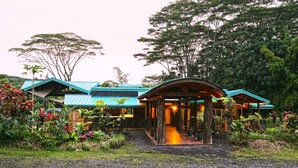A building with a curved roof, surrounded by lush greenery and trees.