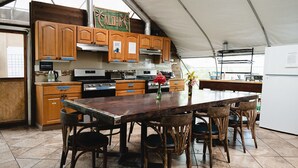 A kitchen with wooden cabinets, a central island, and a dining area with chairs.